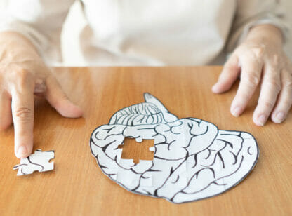 Elderly person piecing together puzzle of brain