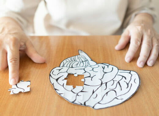 Elderly person piecing together puzzle of brain