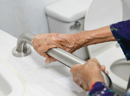 Elderly hands grasping bathtub handle