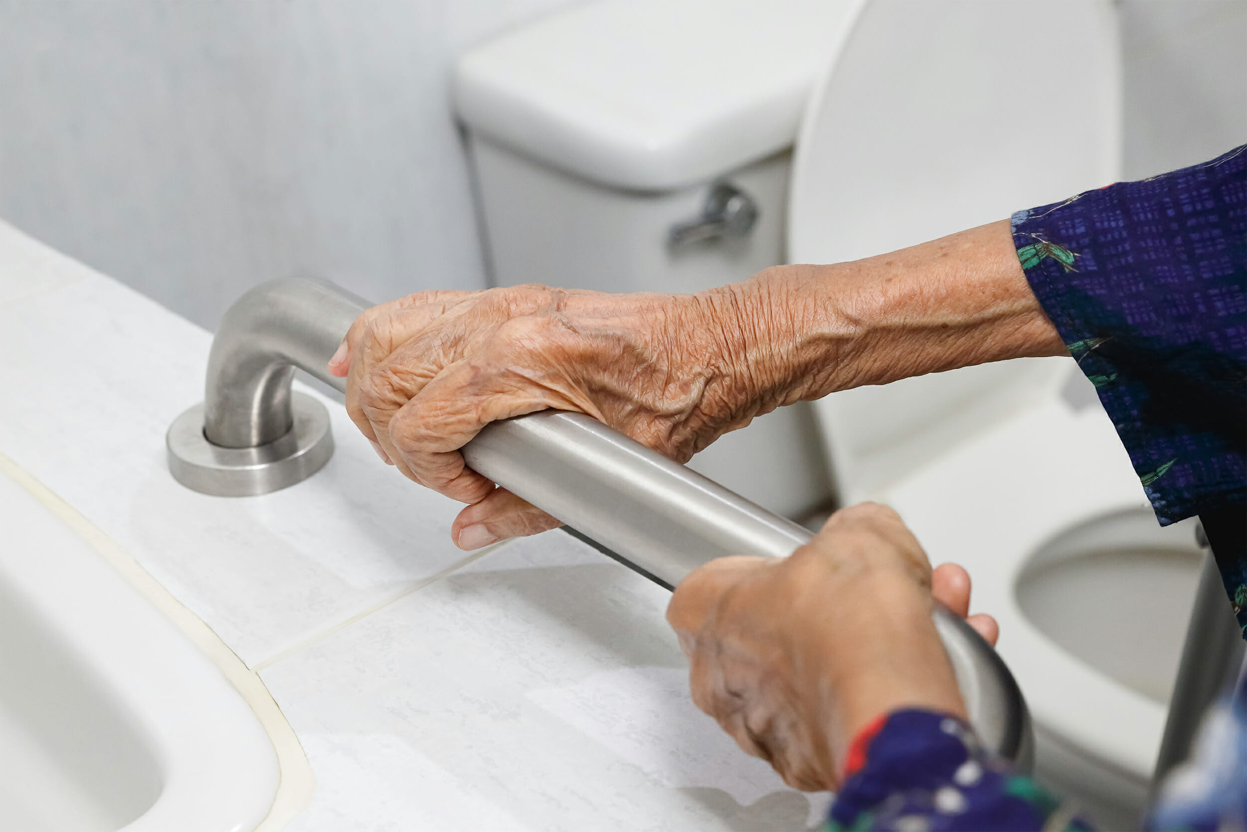 Elderly hands grasping bathtub handle